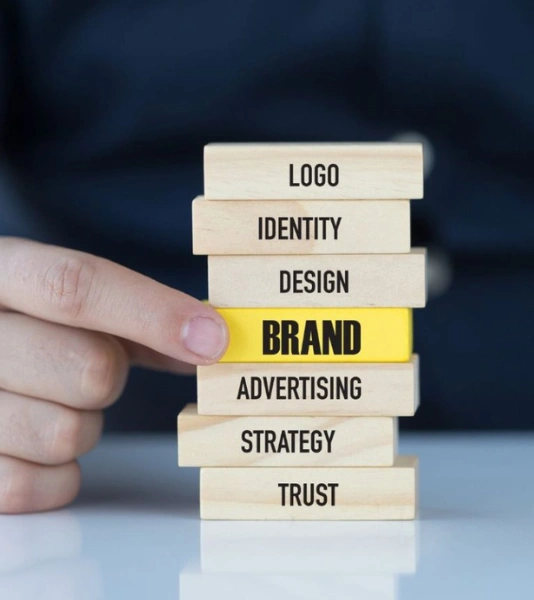 Best Brand Promotion Services for Your Businesses in Bangalore A man holding a wooden block named brand, design, & identity for promotion & advertising strategy.