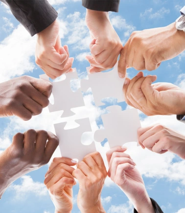 Business professionals assemble puzzle pieces, symbolizing teamwork in media services.